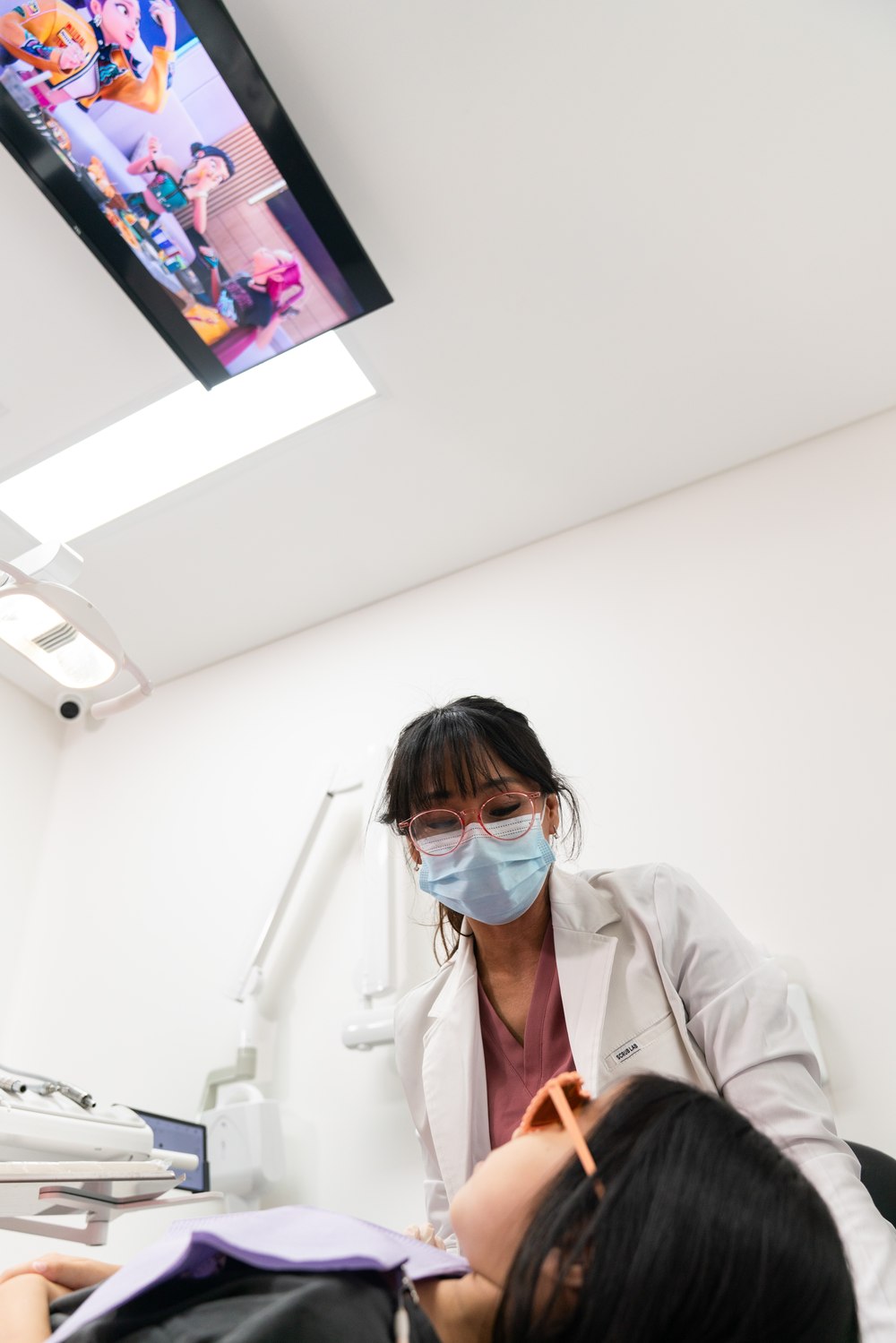 A dentist at Oaks Dental watching a child who is lying relaxed in the chair with a cartoon playing on the ceiling screen above