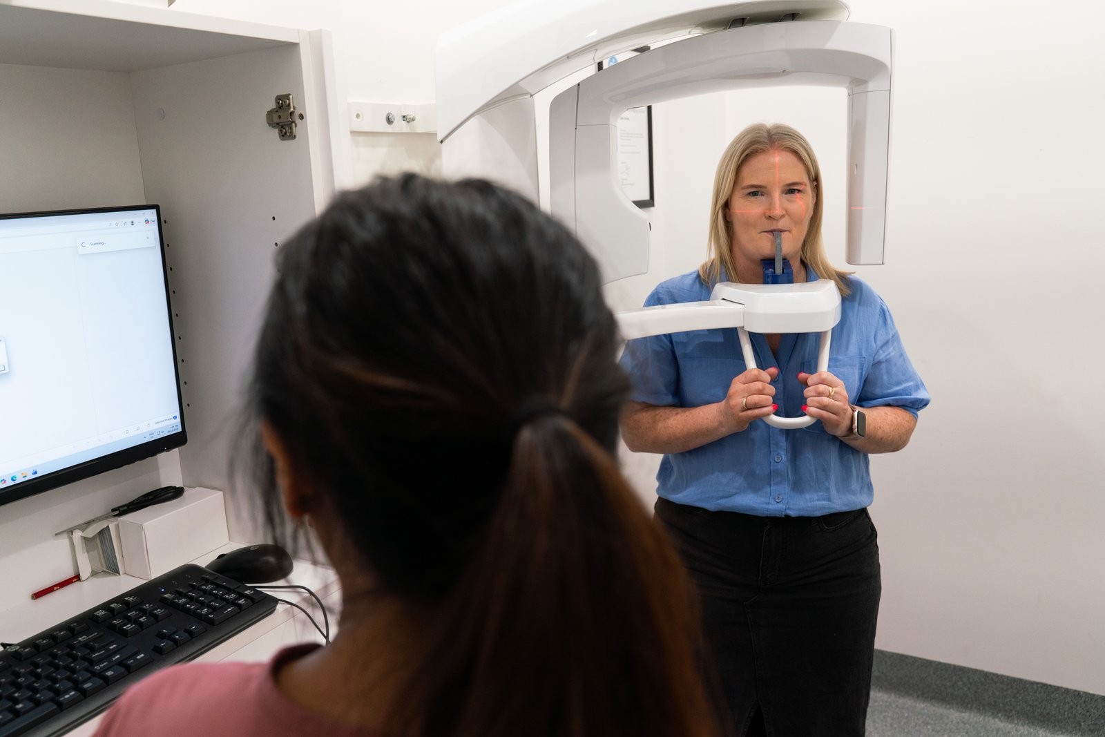 A patient standing in the OPG machine at Oaks Dental while the scan is taken
